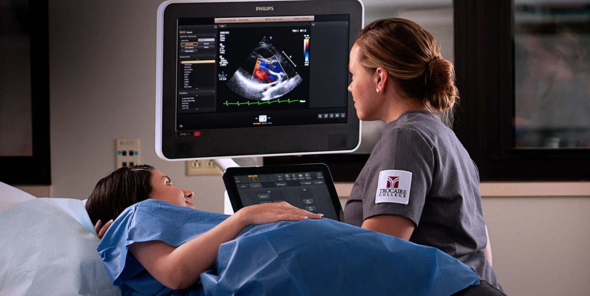 Trocaire student utilizing imaging equipment on a patient.