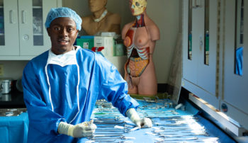 Trocaire student with surgical instruments in a laboratory setting.